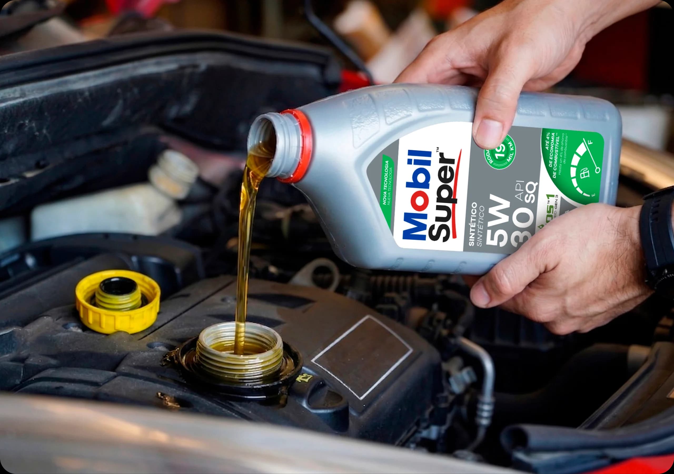 Mãos despejando óleo Mobil Super 5W-30 no motor de um carro durante manutenção automotiva.