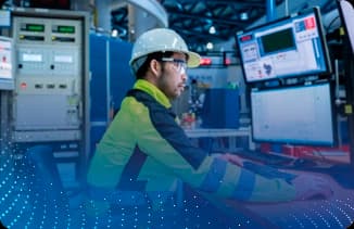 Operador usando painel de controle em ambiente industrial com motor e tubulações ao redor.