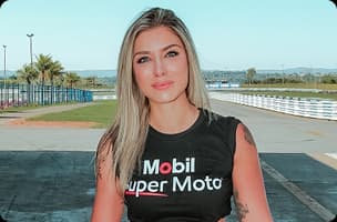 Vans Faria usando camiseta Mobil Super Moto em autódromo com pista e gramado ao fundo.