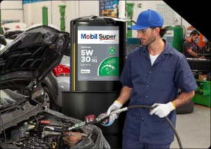 Mecânico em oficina abastecendo motor de carro com óleo Mobil Super 5W-30.