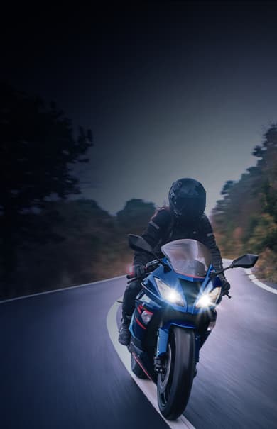 Banner Mobil Super Moto com motociclista pilotando em estrada cercada por árvores.