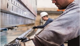 Pessoas trabalhando em uma indústria, cortando metal para ilustrar o uso dos fluidos e lubrificantes metalúrgicos Mobil